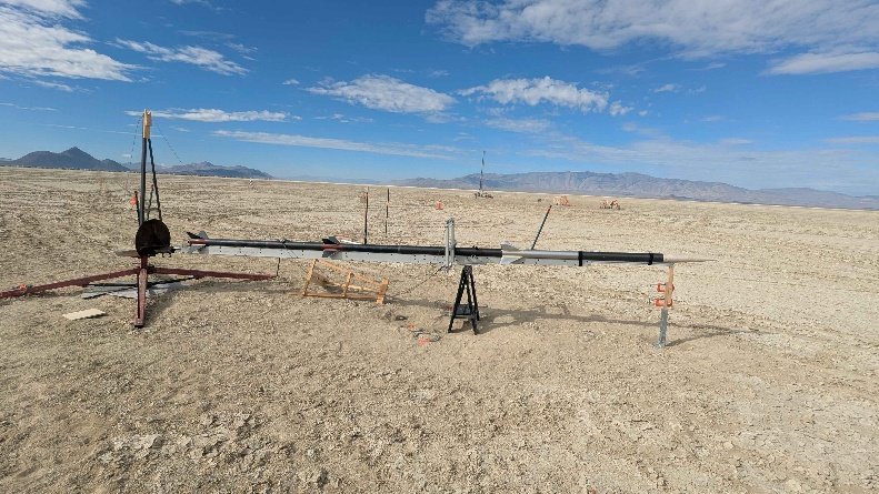 A long rocket resting horizontally on supports at the desert launch site